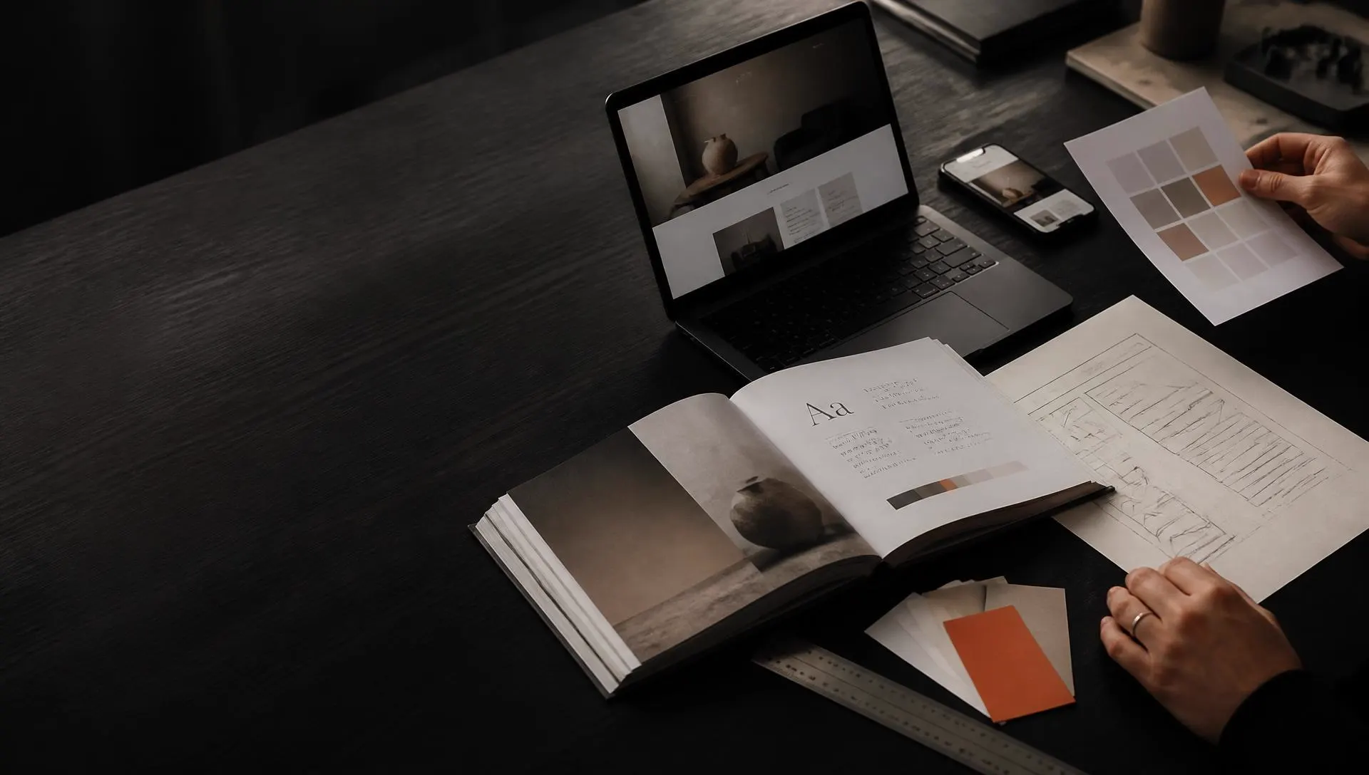 Creative studio worktable with a brand book, colour swatches and a website design on screen