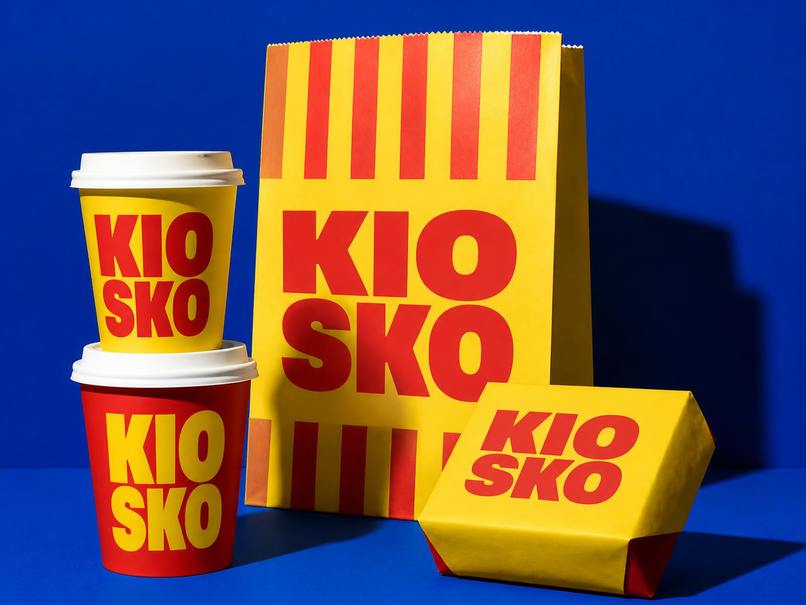 Kiosko packaging: yellow and red cups, striped paper bag and wrapped box on blue